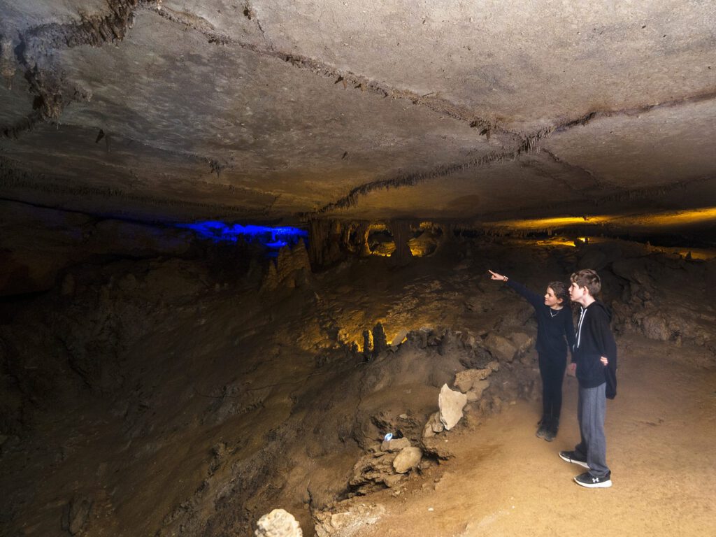 Two kids pointing at stalactites inside the caverns