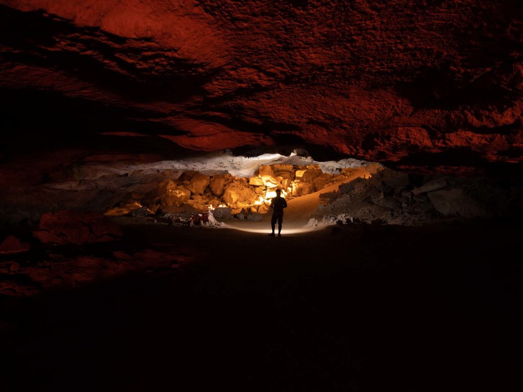 Person standing in the caverns with a lamp on