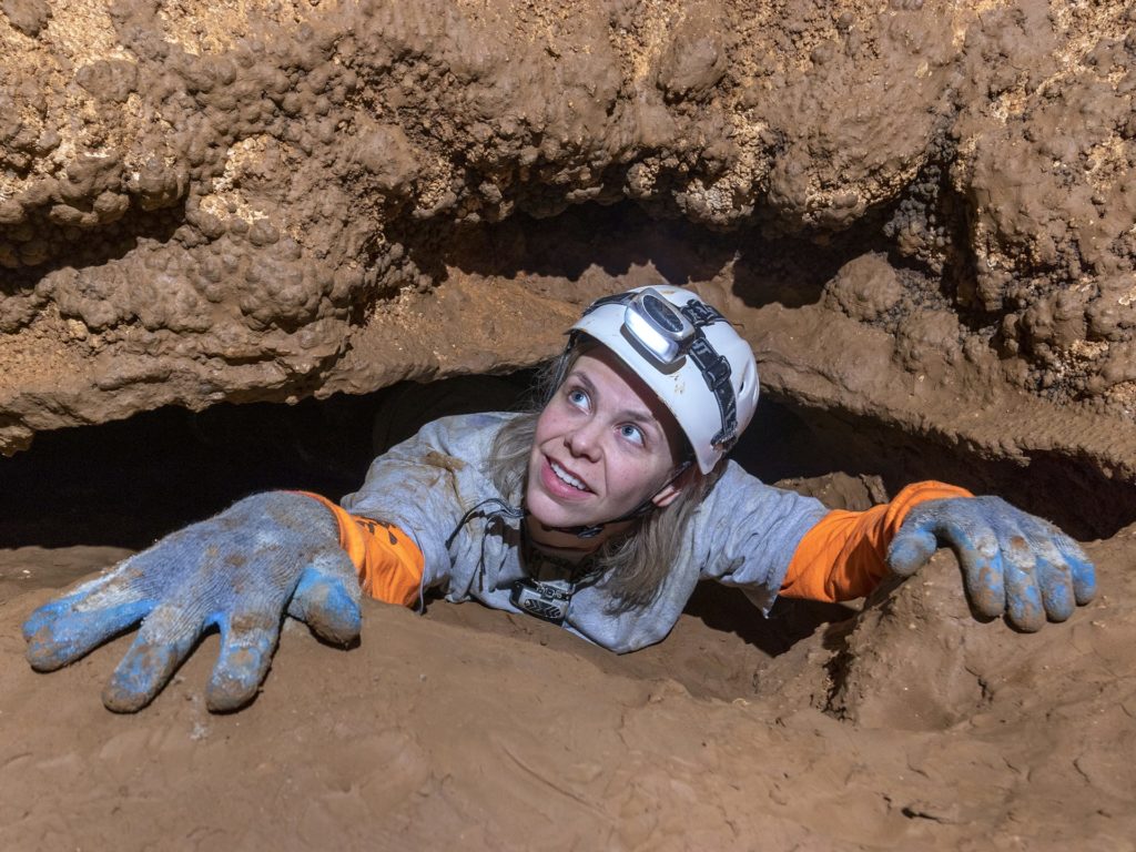 Woman climbing up rocks inside the caverns