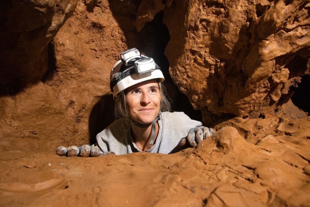Older woman climbing up rocks inside the caverns