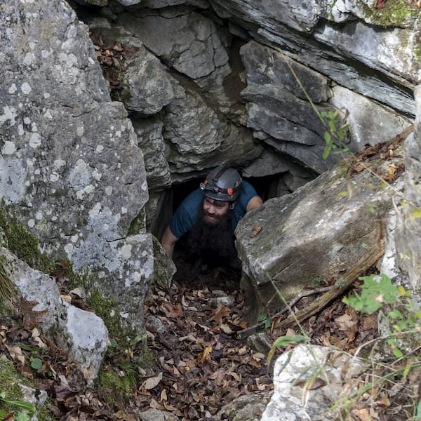 Man crawling through rocks to outside area of Caverns