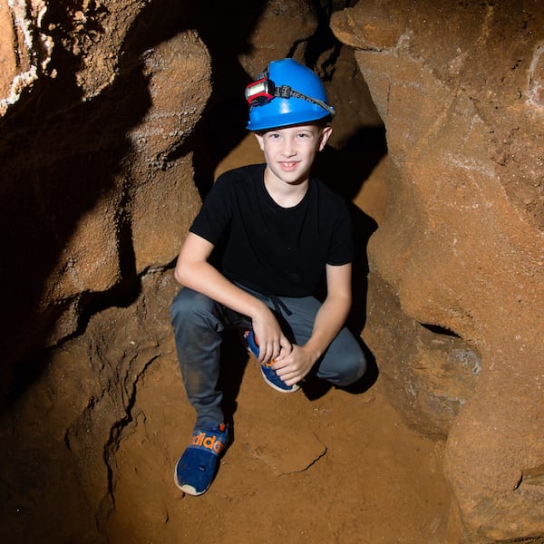 Kid squatting and smiling for a photo in the caverns