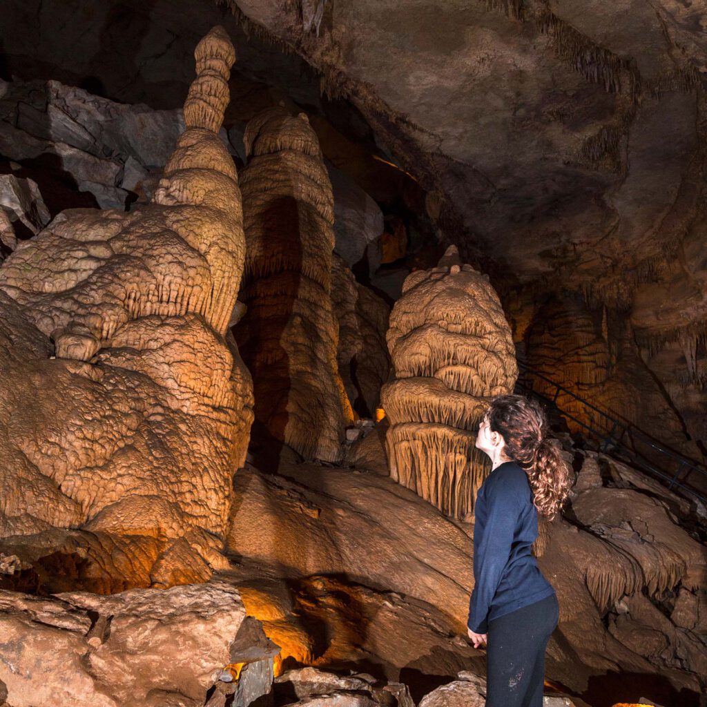 Girl looking up at a stalagmite in the caverns